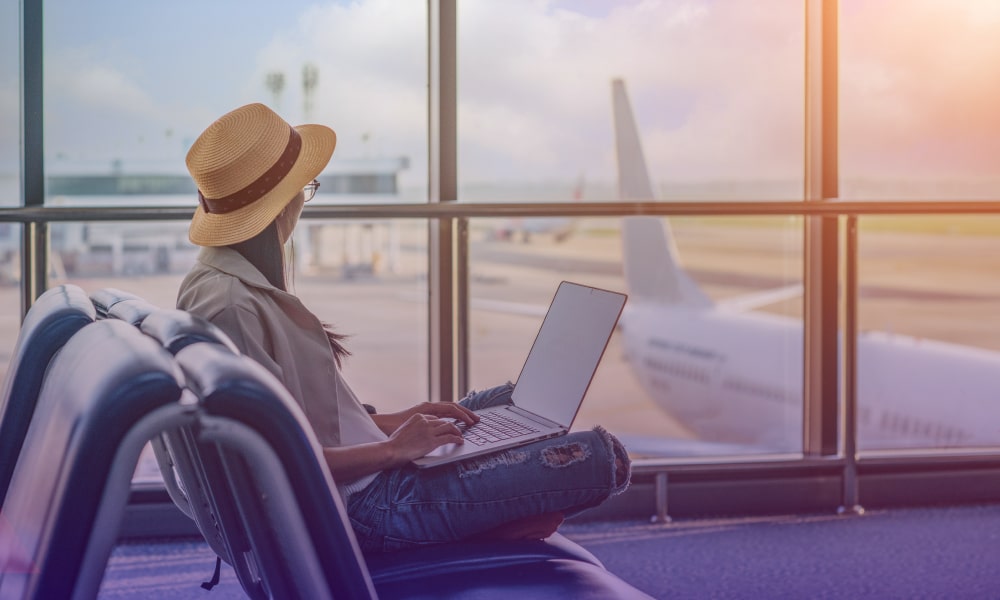 Cliente sentada no aeroporto com notebook no colo aproveitando a Rede Privativa para automatizar processos de trabalho.